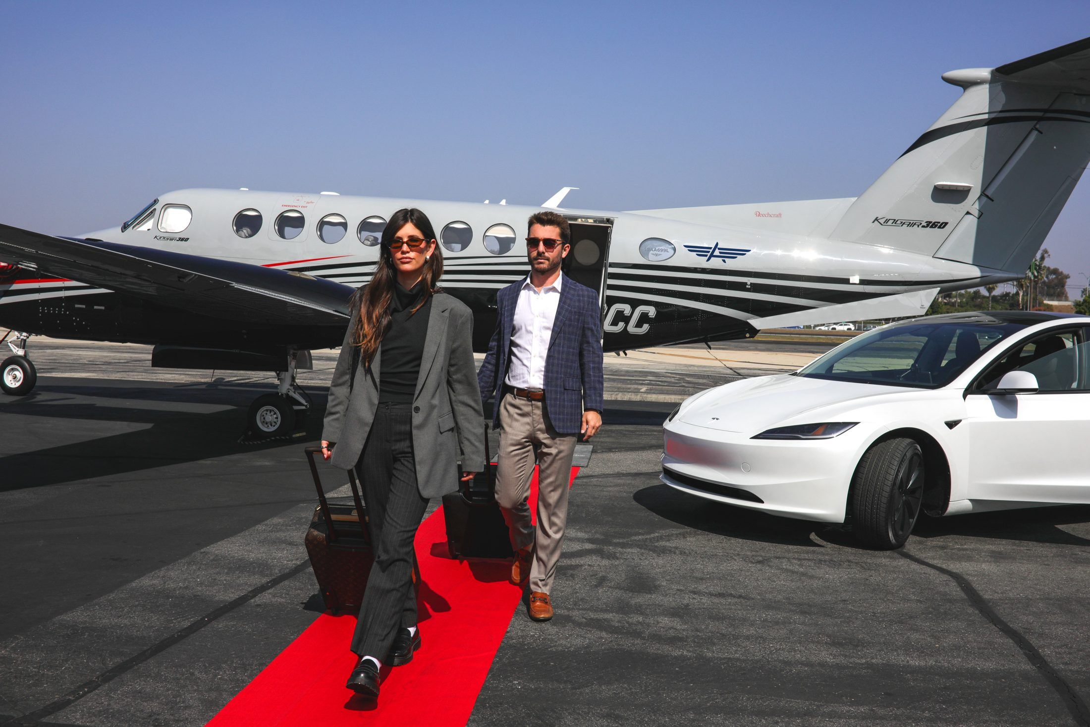 Two travelers walking the red carpet from an Advanced Air Charters King Air 360 at Hawthorne Municipal Airport