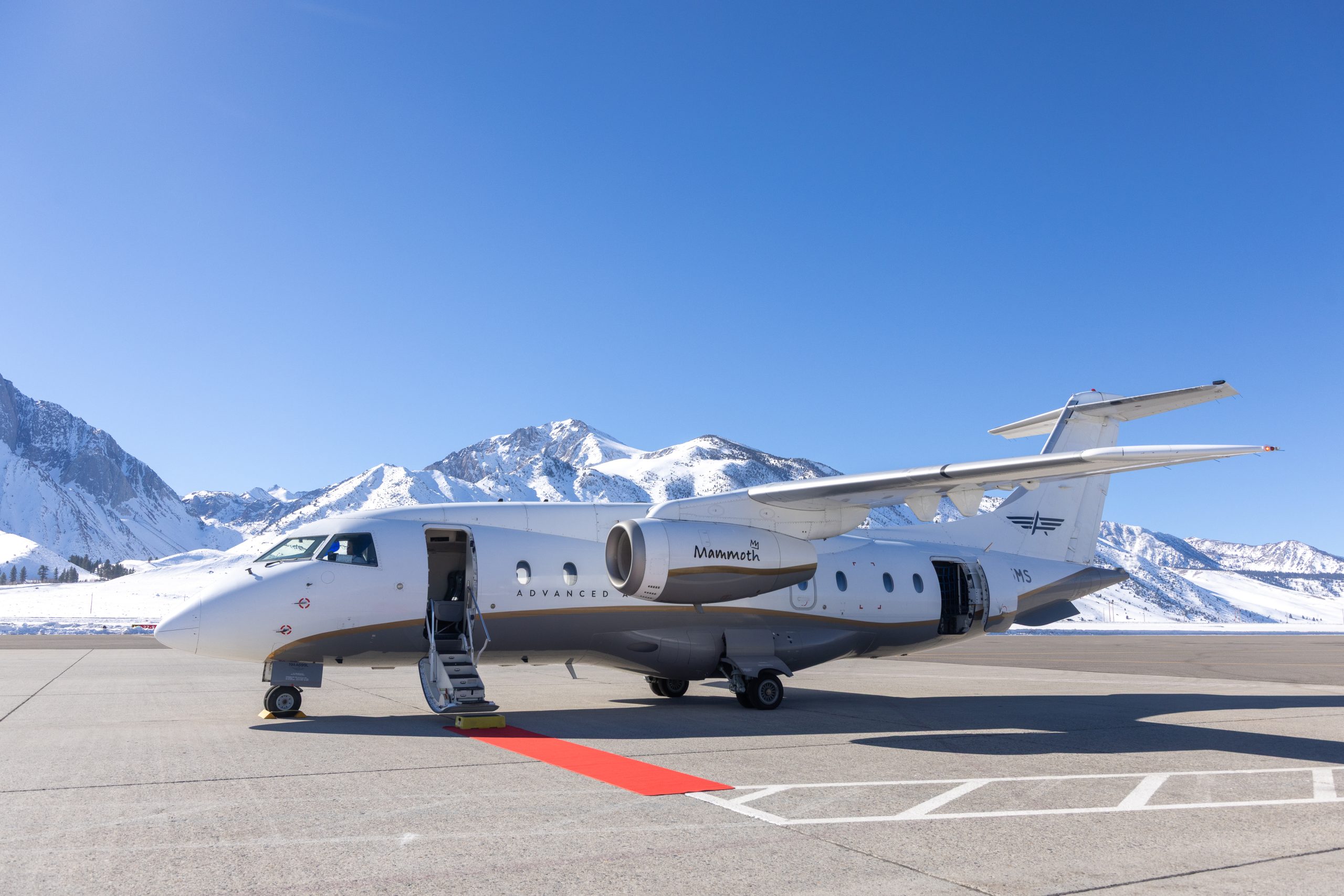 Advanced Air Dornier 328 aircraft at Mammoth Yosemite Airport with snow-capped mountains in the background